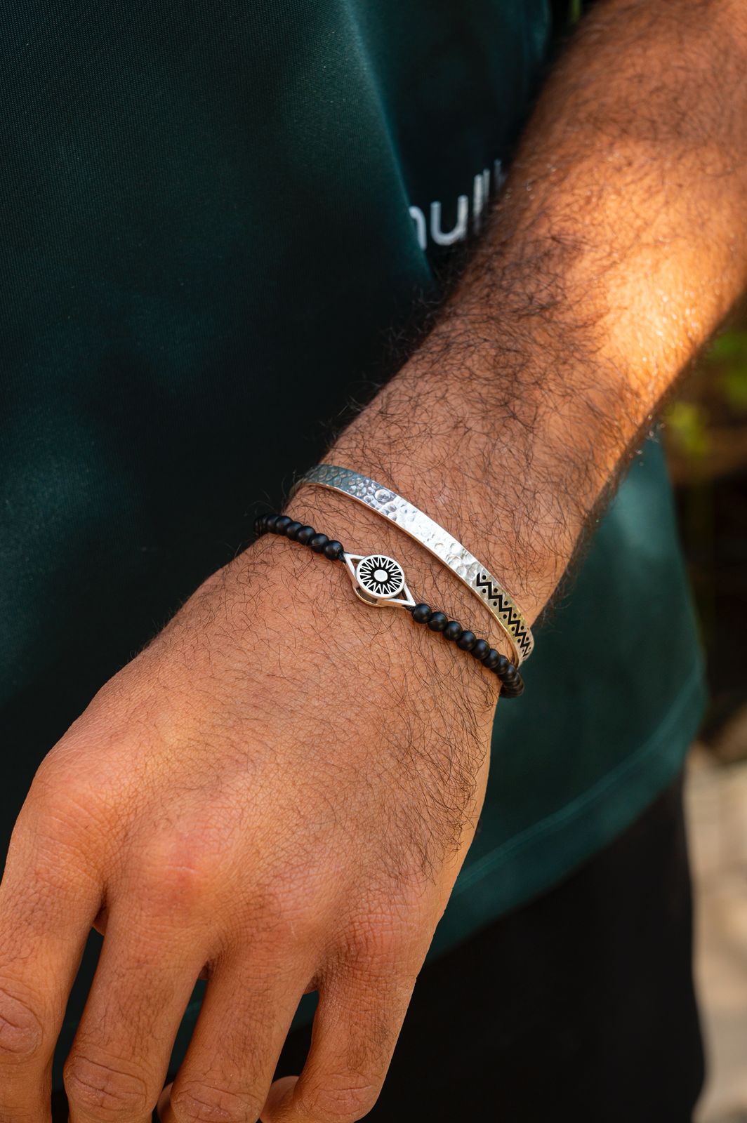Close-up of a person's wrist wearing two bracelets with a blurred background
